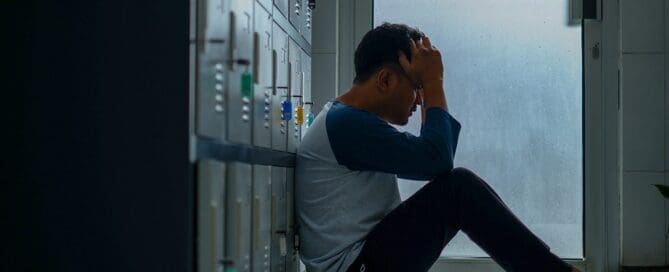 teen sitting in school hallway depressed