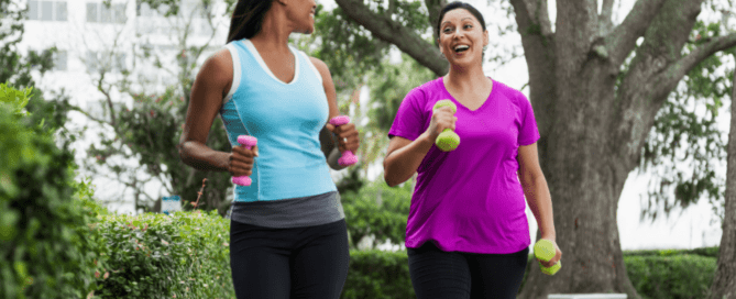 Two woman jogging while holding dumbbells