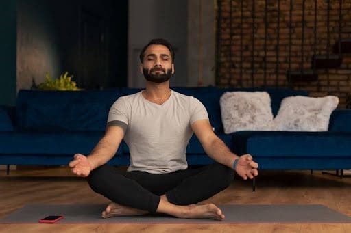 man meditating in living room