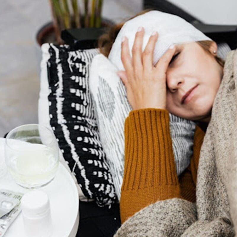 woman laying on couch with compress on head