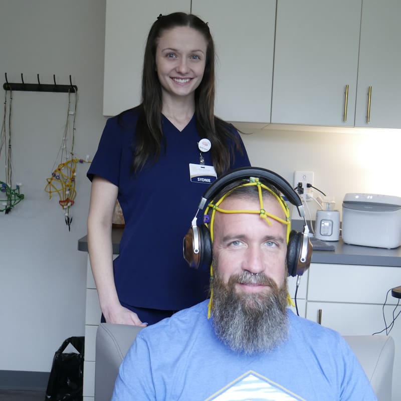 Sydnie and patient with yellow cap Neurofeedback Patient with Practitioner