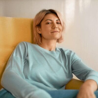 pretty-girl-with-bob-pink-hairstyle-nose-ring-sitting-comfortably-armchair