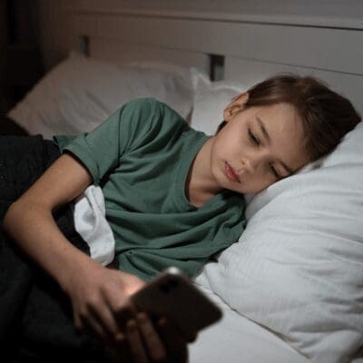 kid with screen addiction, using phone in bed, past bedtime