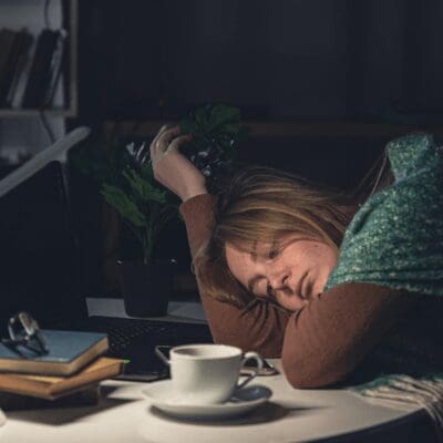 tired young woman lays down her head on her desk to rest